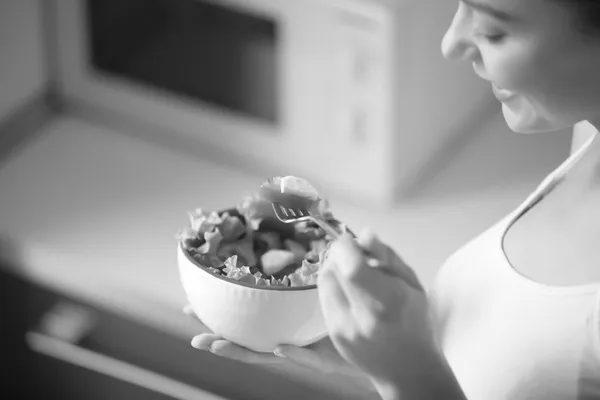 Una mujer comiendo ensalada de un bowl.